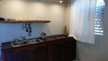 Una cocina con mostrador de madera, un lavamanos y una ventana con persianas.