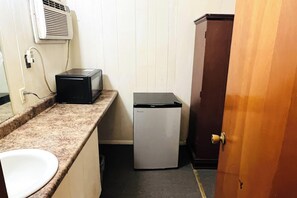 Una kitchenette compacta con encimera, lavamanos y un refrigerador pequeño.