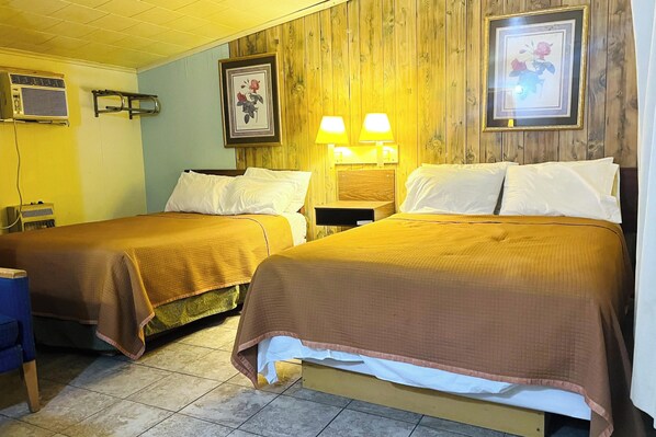 Two twin beds with brown bedding, a wooden wall panel, a framed floral picture, and a wall-mounted lamp. - Sparta Motel Near St. Louis / Mississippi River IL (Sparta)