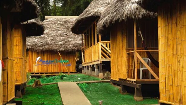 Une structure traditionnelle en bois, avec un toit de chaume, une terrasse en bois et un mur en bambou.