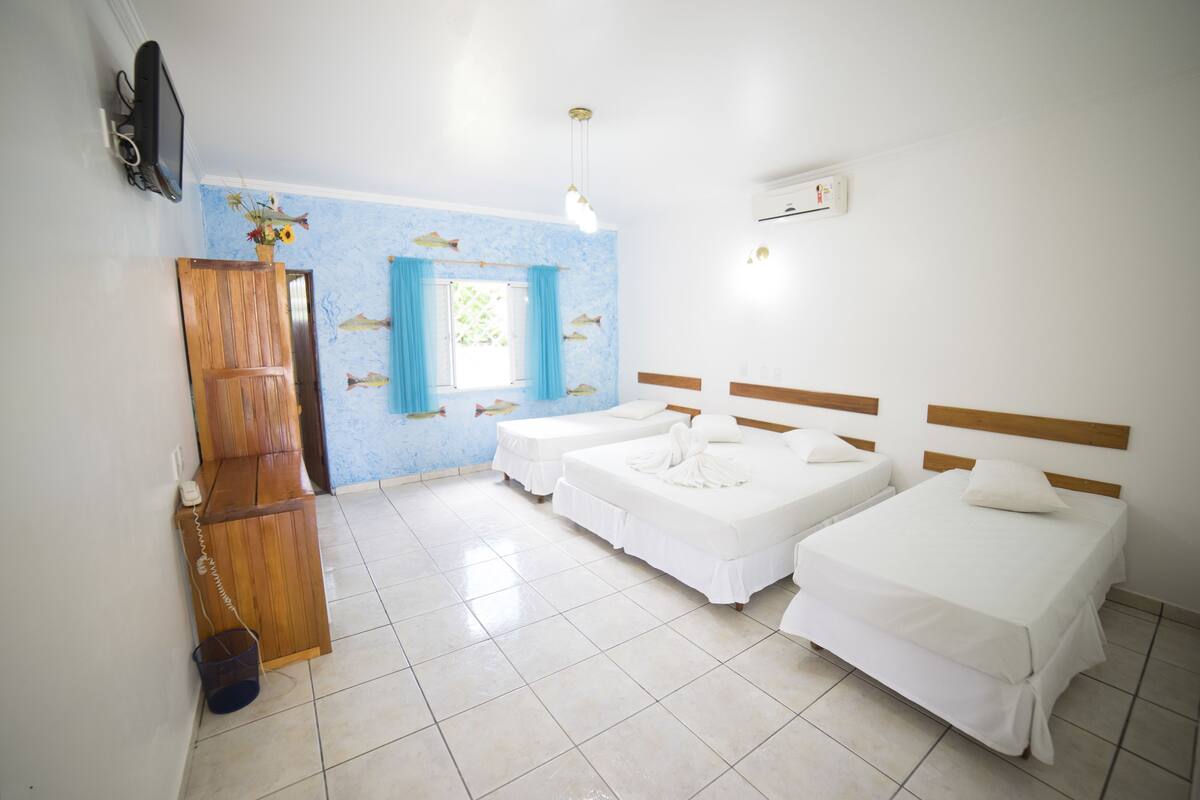 Una habitación de hotel con dos camas individuales, un armario de madera, un pequeño escritorio con teléfono y una pared decorada con peces.