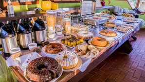 Un bufé con diversos alimentos, incluyendo pasteles, productos de repostería y bebidas calientes.