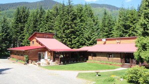 A log cabin with a red roof, a porch, and a small garden area. - Shames Country Lodge (Terrace)