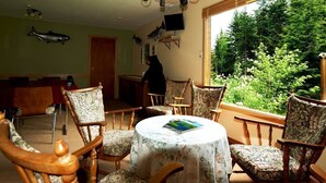 A cozy room with a round table, floral-patterned chairs, and a large window offering a view of greenery. - Shames Country Lodge (Terrace)