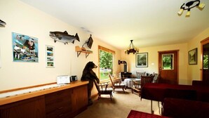 A cozy kitchen with wooden cabinets, a dining area with chairs, and a bear sculpture on the wall. - Shames Country Lodge (Terrace)