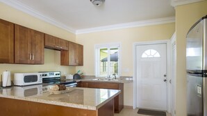 Una cocina con armarios de madera, microondas, estufa, fregadero y refrigerador.