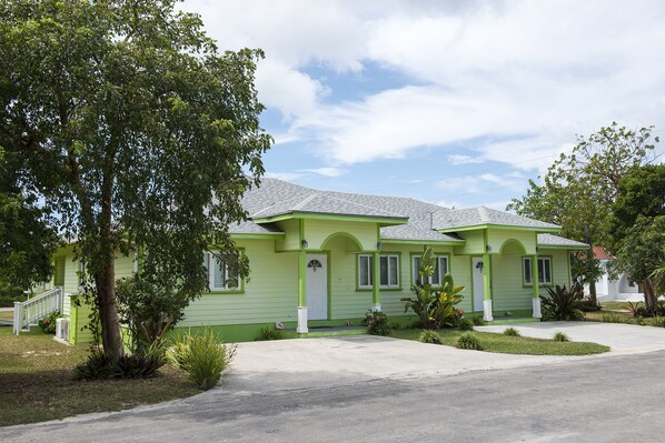 A two-story house with a green exterior, a front porch, and a driveway. - Sir Charles Guest House (South Palmetto Point)