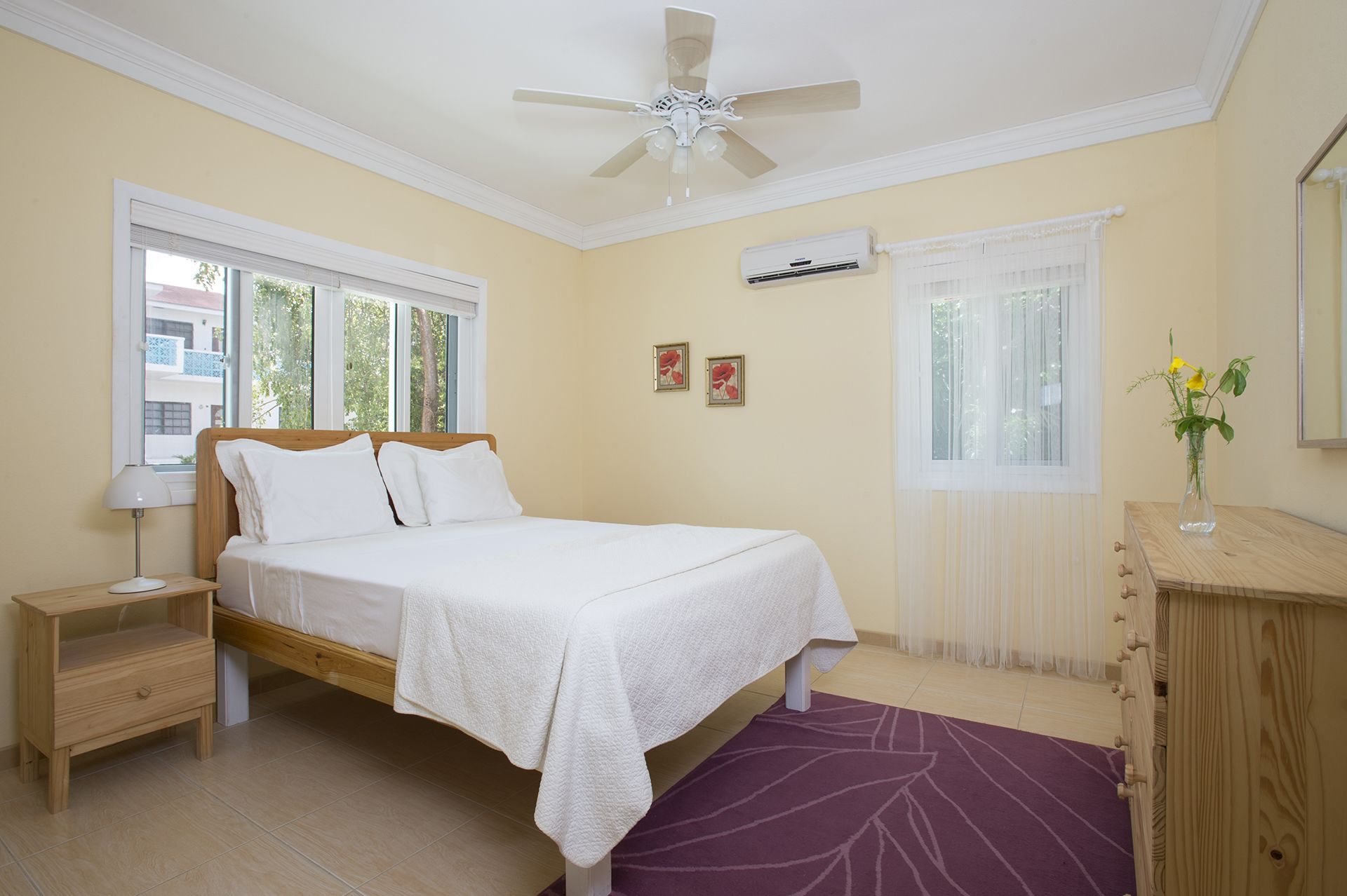 Une chambre à coucher comprenant un lit, une table de chevet, une commode et un ventilateur de plafond.