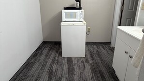 A compact laundry room with a white washing machine, a small coffee maker, and a sink. - Regency Inn and Suites (Dodge City)