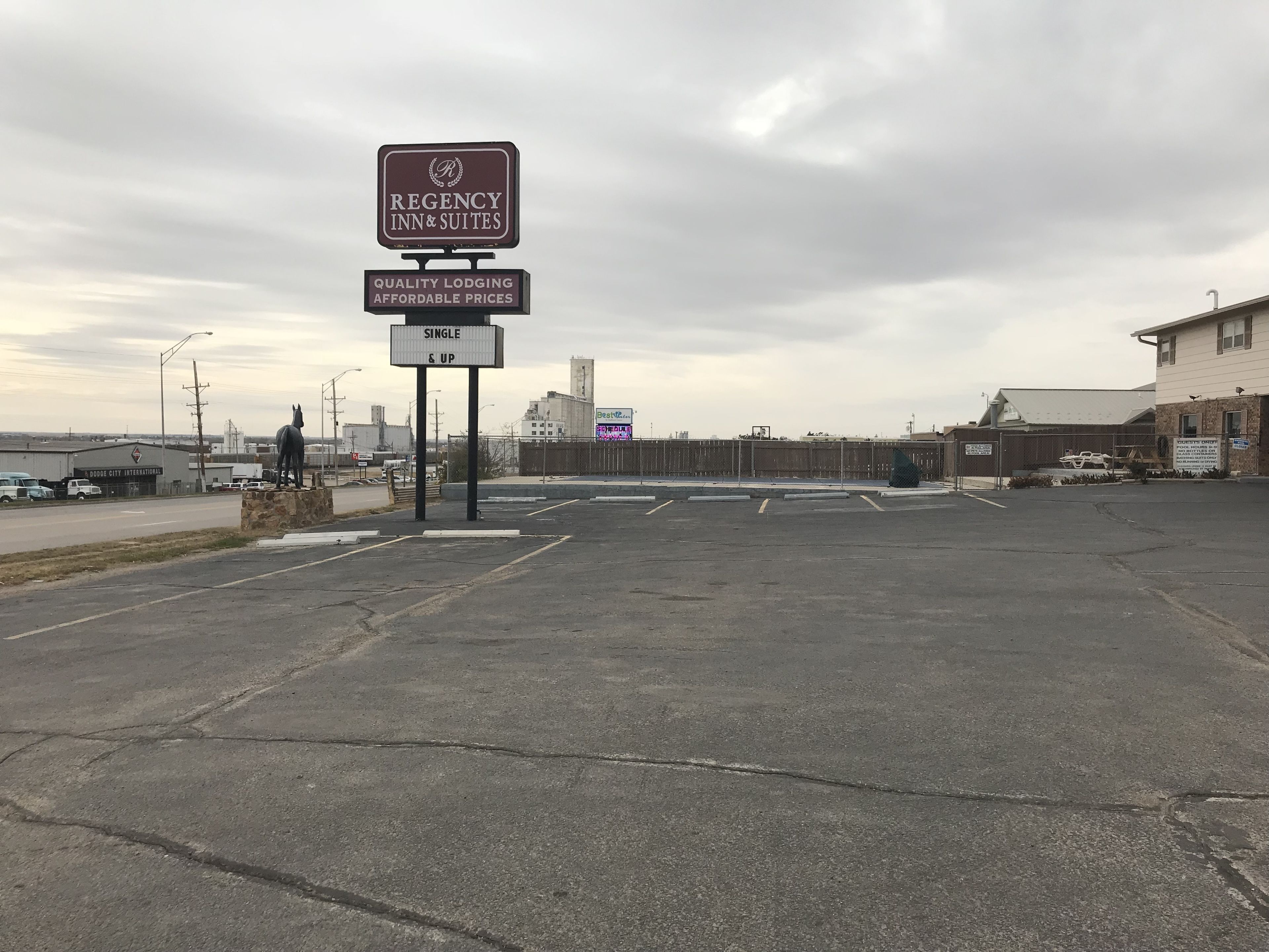 A parking lot with a sign for Regency Inn & Suites, indicating single and up accommodations.