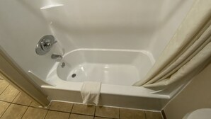A white bathtub with a shower curtain, a towel, and a chrome faucet. - Regency Inn and Suites (Dodge City)