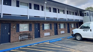 A two-story building with numbered doors, a parking area, and a white van parked in front. - Regency Inn and Suites (Dodge City)