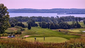 A golf course with a lake in the background, surrounded by trees and rolling hills. - Bellmere Winds Resort (Otonabee-South Monaghan)