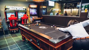 Ein Billardtisch mit einer Person beim Spiel, Spielautomaten und eine Bar.