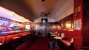 Eine Bar mit Theke, Hockern und einer Sitzecke mit Tischen und Stühlen.