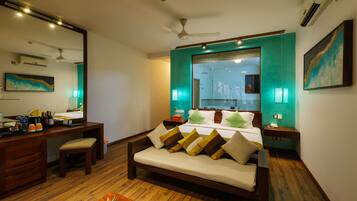 A modern hotel room with a bed, a desk, and a seating area.