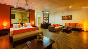 A modern hotel room with a large bed, a sofa, a coffee table, and a dining table. There is a mirror on the wall and a ceiling fan. - Cocobay Unawatuna (Unawatuna)