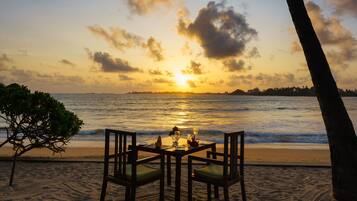 A beachside table with chairs and a sunset view.