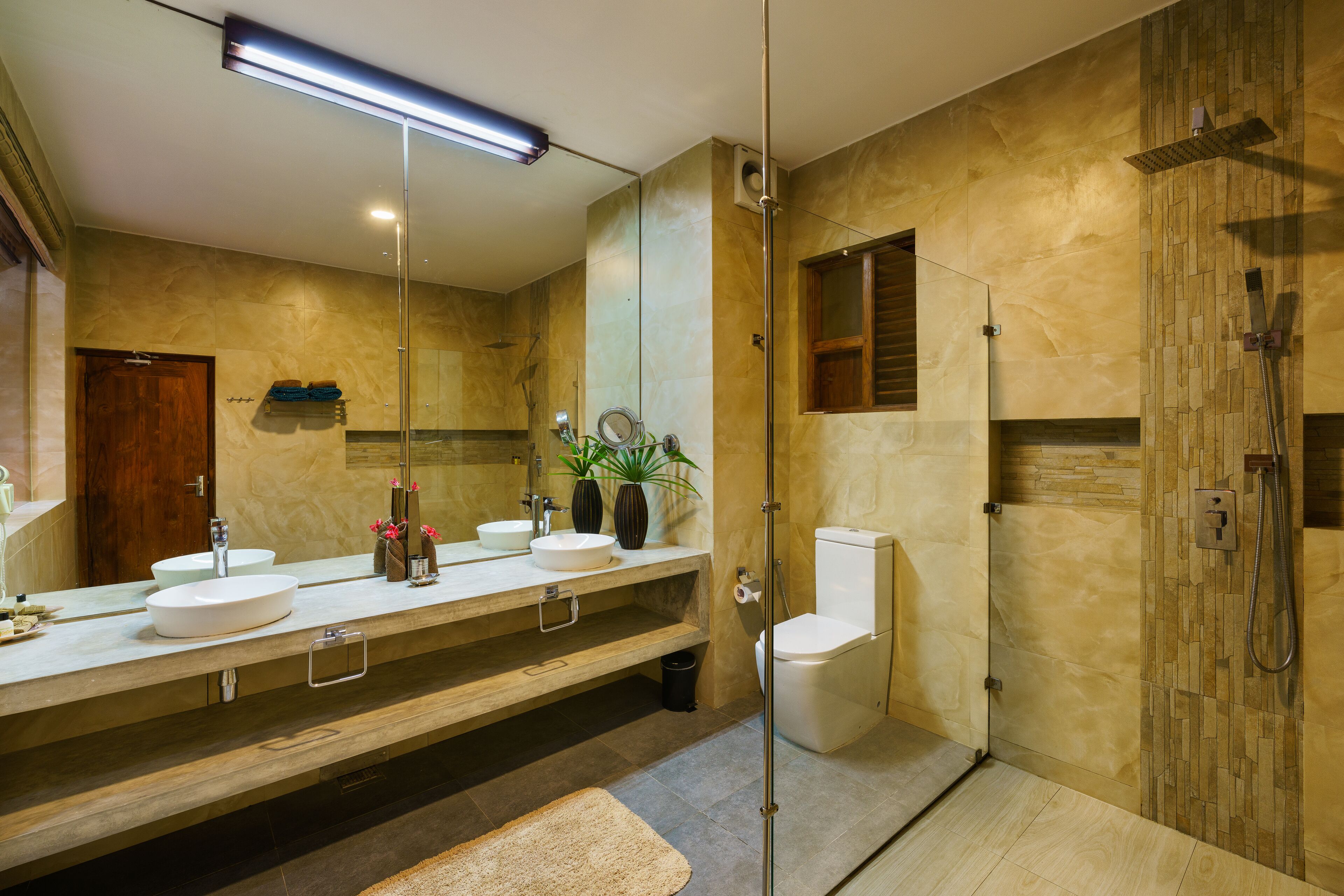 A modern bathroom with two sinks, a toilet, and a shower area.
