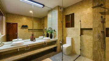 A modern bathroom with two sinks, a toilet, and a shower area.