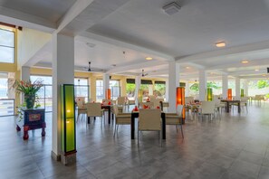 A spacious indoor dining area with high ceilings, large windows, and modern furniture.