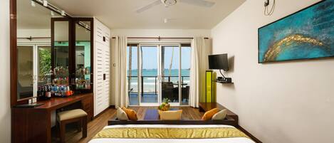 A hotel room with a bed, a desk, a chair, a television, and a view of the ocean.