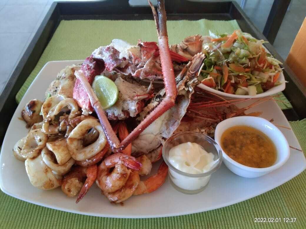 A seafood platter with shrimp, squid, and lobster, accompanied by a salad and two dipping sauces.