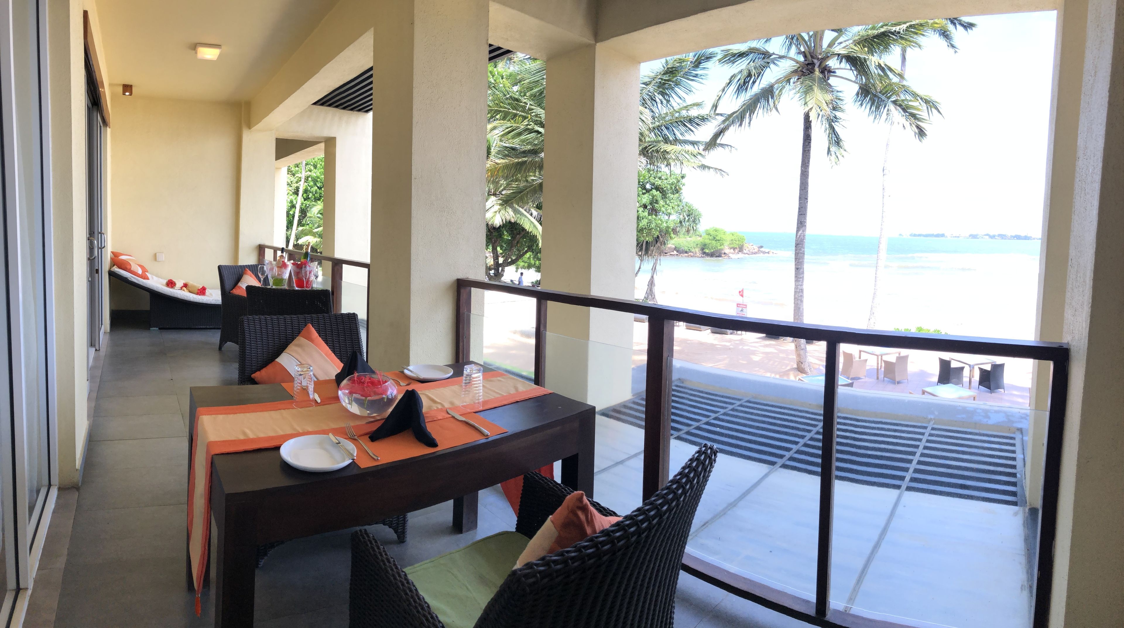 A dining area with a table set for two, overlooking a beach.