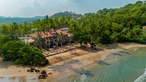 A beachfront property with a pool area, palm trees, and a view of the ocean. - Cocobay Unawatuna (Unawatuna)