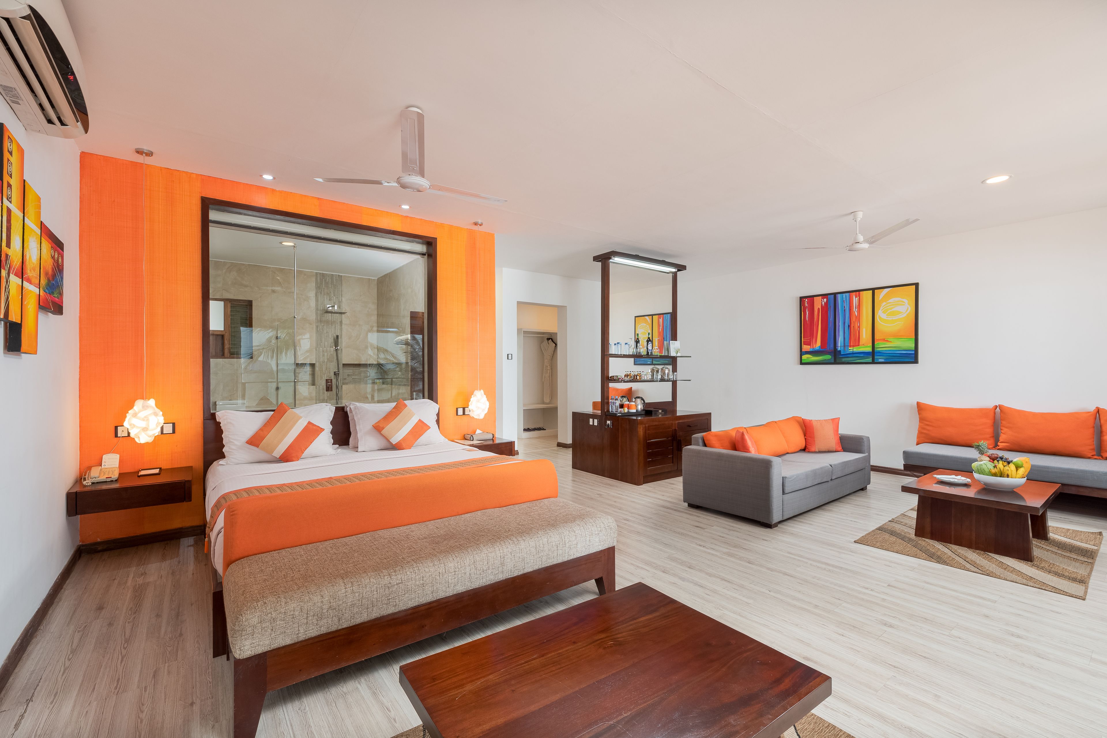 A modern hotel room with a large bed, a sofa, a desk, and a bathroom.