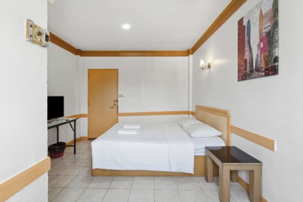 Une chambre d’hôtel avec un lit, une petite table, une télévision et une porte.