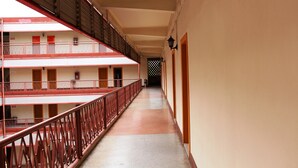 A corridor with multiple balconies, each with a red railing and a door. - Phu Inn Hotel (Khon Kaen)