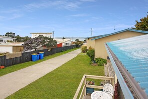A residential backyard with a concrete path, a wooden fence, and a blue-roofed building. - Carmens Inn (Scamander)