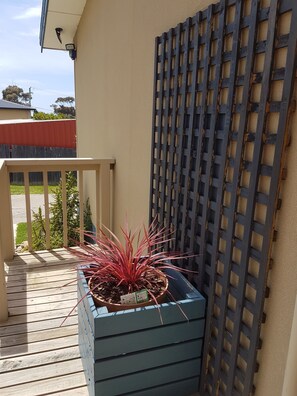 A wooden deck with a planter box containing a plant with red leaves. - Carmens Inn (Scamander)