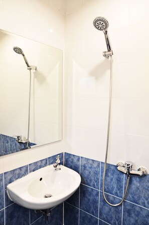 A bathroom with a white sink, a mirror, a handheld showerhead, and a wall-mounted showerhead. - Erawan House (Bangkok)