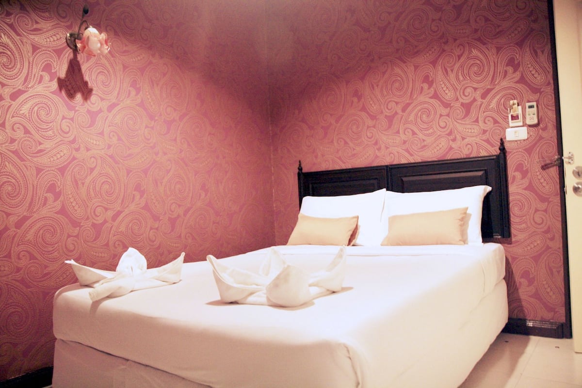 Een hotelkamer met een bed, een hoofdbord, een wandklok en een deur.