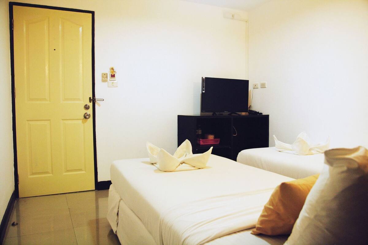 Een hotelkamer met twee bedden, een televisie en een deur.