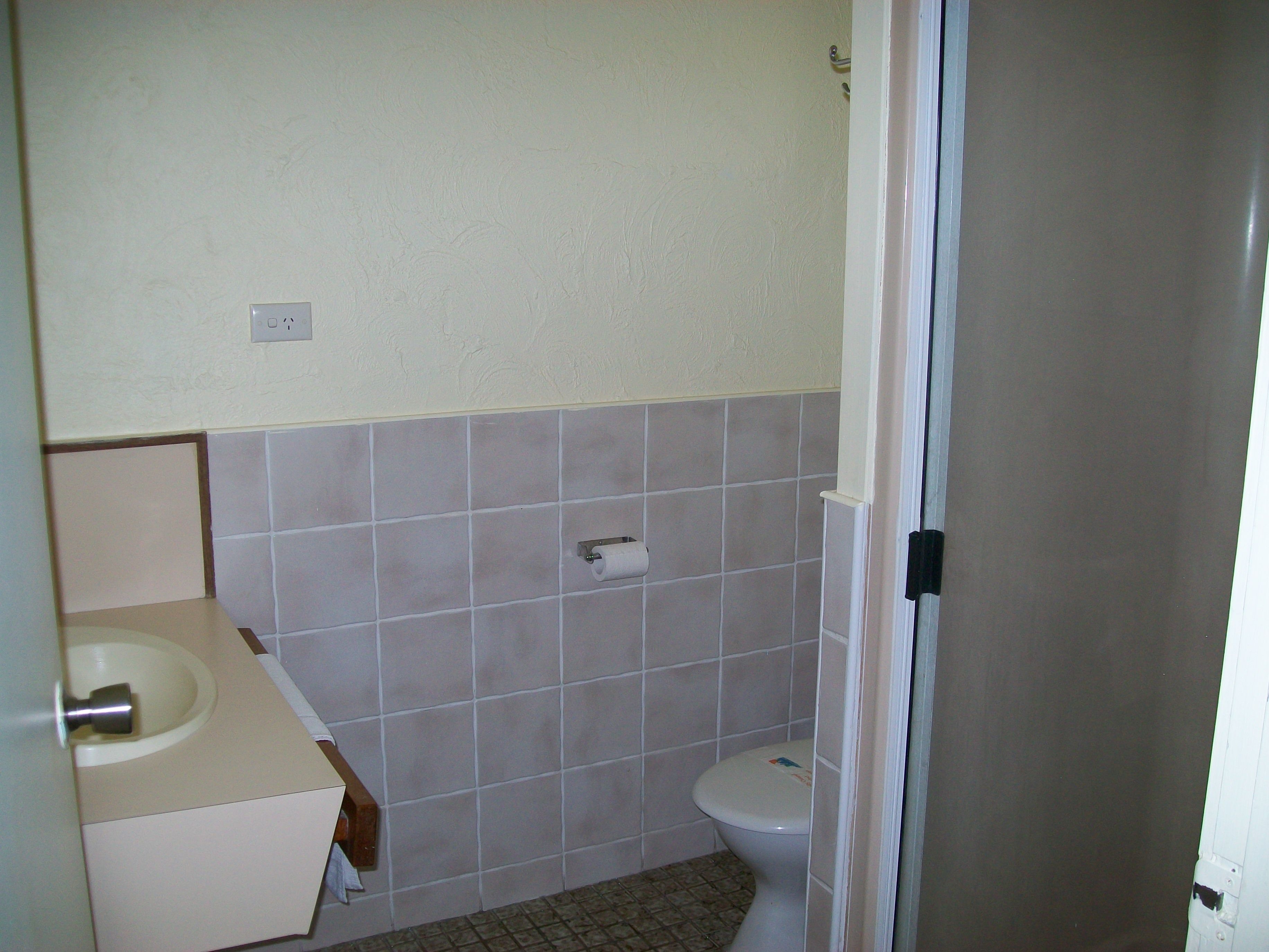 A small bathroom with a toilet, sink, and tiled walls.