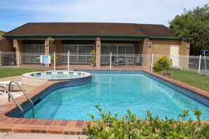 A swimming pool with a hot tub, surrounded by a fenced patio area. - Sun Plaza Motel Mackay (West Mackay)