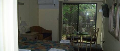 Una habitación de hotel con una cama, un escritorio con lámpara, televisión, una silla y vistas al exterior.