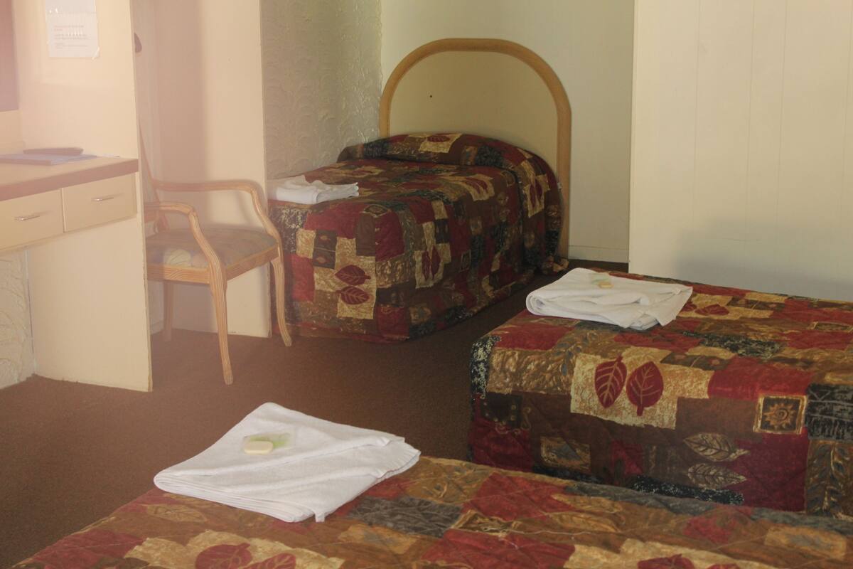 A room with two beds, a desk, and a chair.