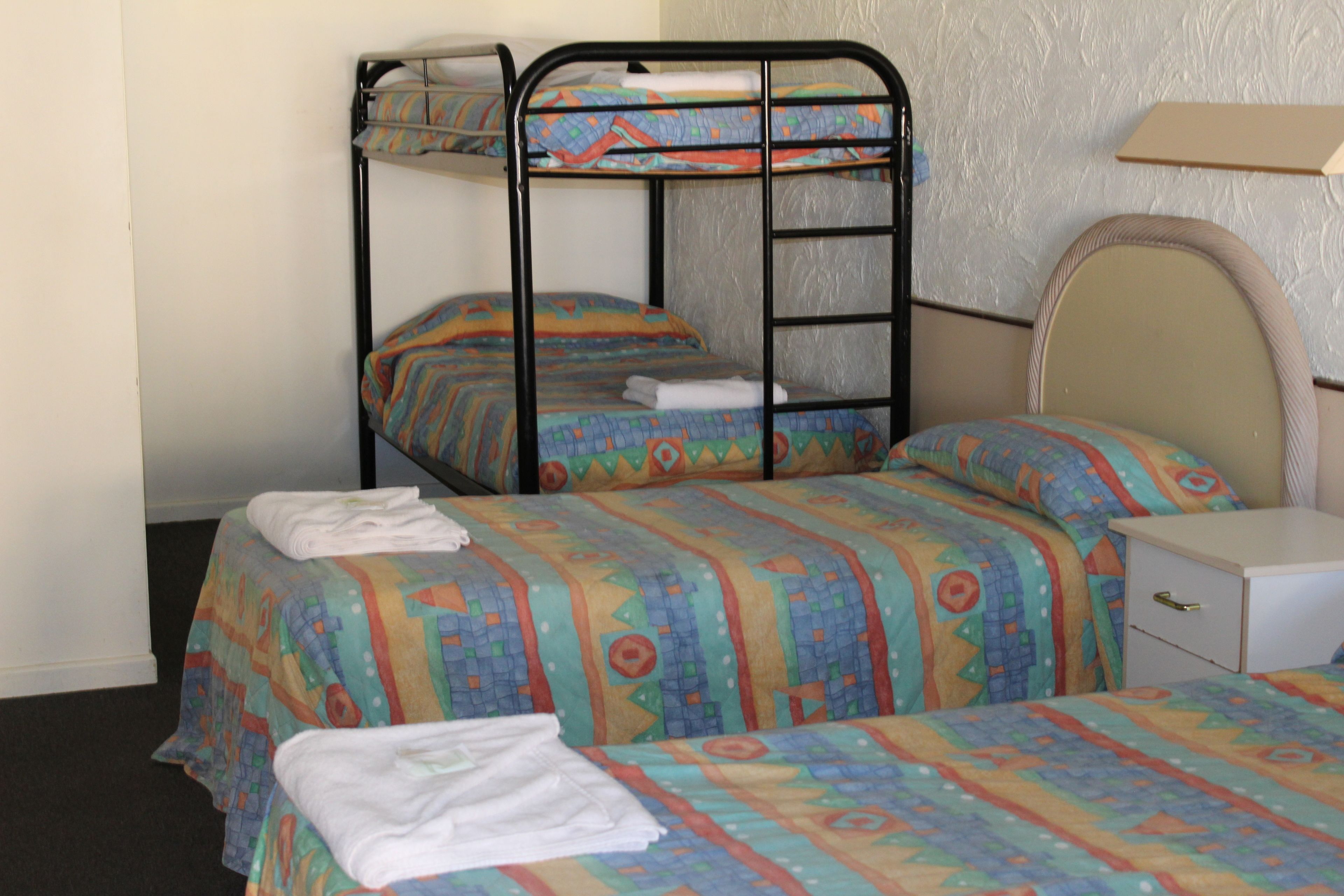 Une chambre avec deux lits superposés, une table de chevet et une petite commode.