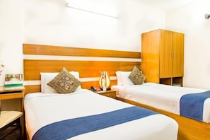 Ein Hotelzimmer mit zwei Einzelbetten, einem Holzkopfteil, einem Kleiderschrank, einem Nachttisch und einer Lampe.