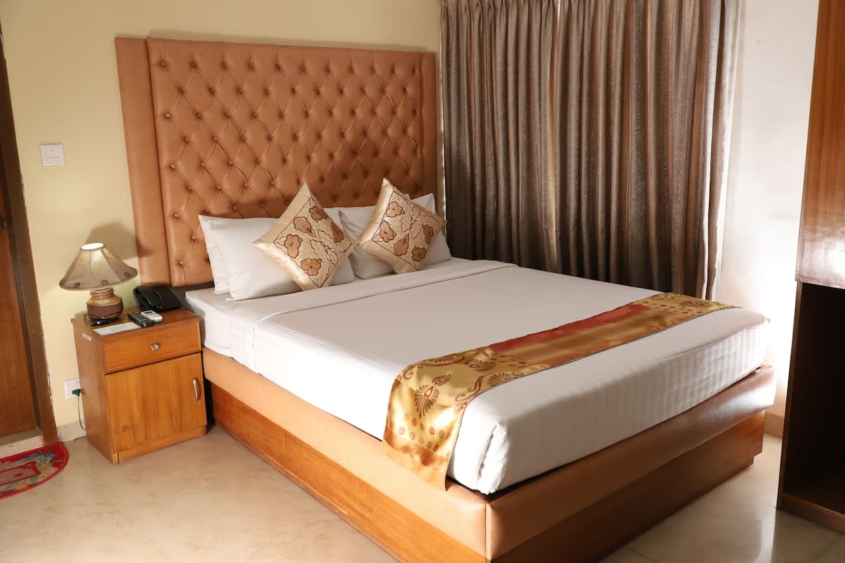 A neatly made bed with a tufted headboard, a bedside table with a lamp, and a patterned throw blanket.