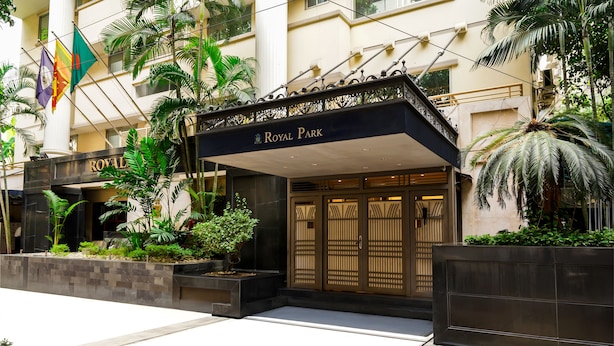 The entrance of the Royal Park hotel with a modern facade, large glass doors, and a covered entrance area.