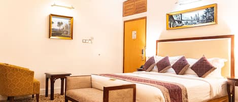 A hotel room with a large bed, a sofa, a small table, and two wall-mounted lamps.