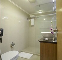 Un baño moderno con inodoro, lavamanos y zona de ducha.