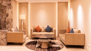 A modern living room with a beige sofa, two armchairs, a coffee table, and a lamp.