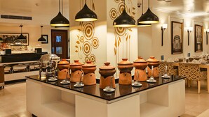 A modern kitchen with a central island, black pendant lights, and decorative wall patterns.