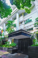 Entrada de hotel con marquesina, palmeras y una bandera.